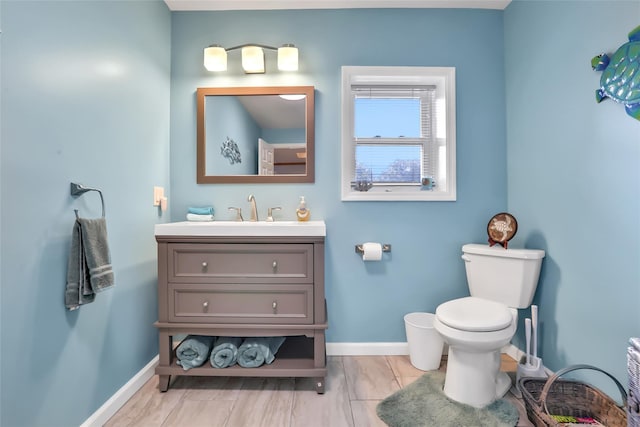 bathroom with vanity, toilet, and baseboards