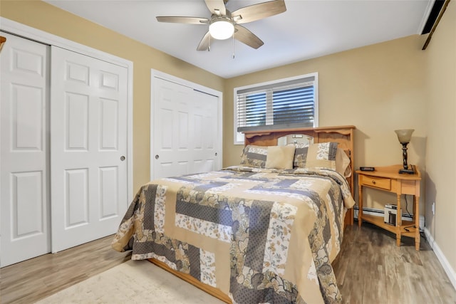 bedroom featuring baseboards, wood finished floors, a ceiling fan, and multiple closets