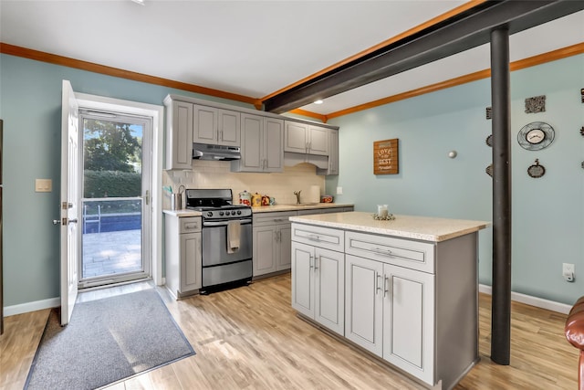 kitchen with under cabinet range hood, light countertops, gray cabinets, stainless steel range with gas cooktop, and light wood finished floors