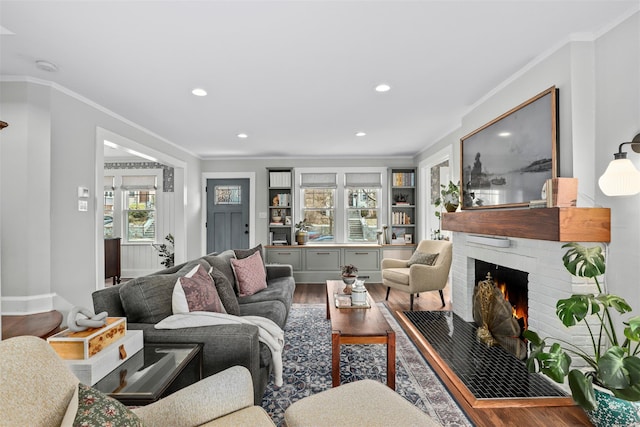 living room with crown molding, wood-type flooring, and a fireplace