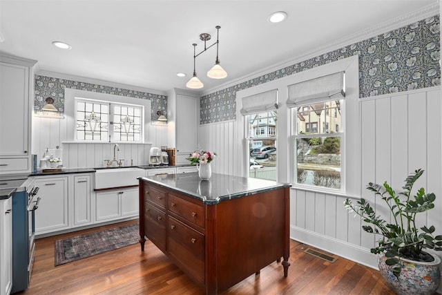 kitchen with pendant lighting, sink, dark wood-type flooring, white cabinetry, and a center island