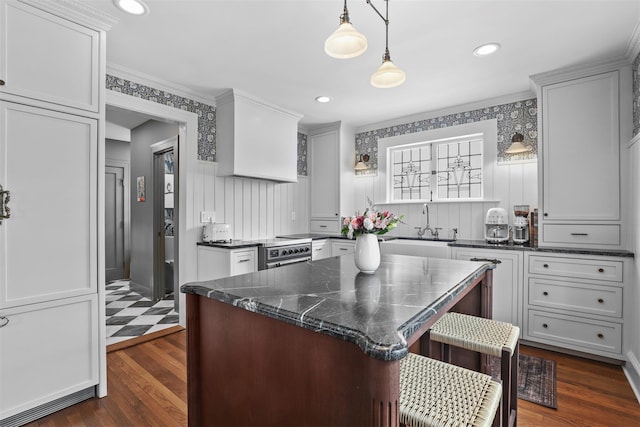 kitchen featuring sink, hanging light fixtures, a kitchen breakfast bar, a kitchen island, and dark stone counters