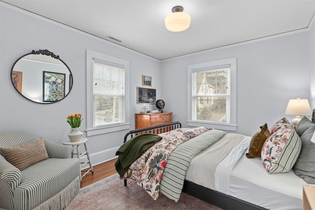 bedroom with multiple windows, wood-type flooring, and ornamental molding