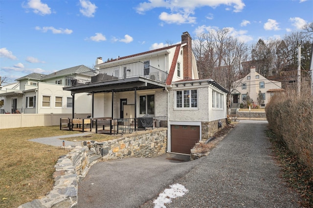 back of house featuring a yard, a garage, and a balcony