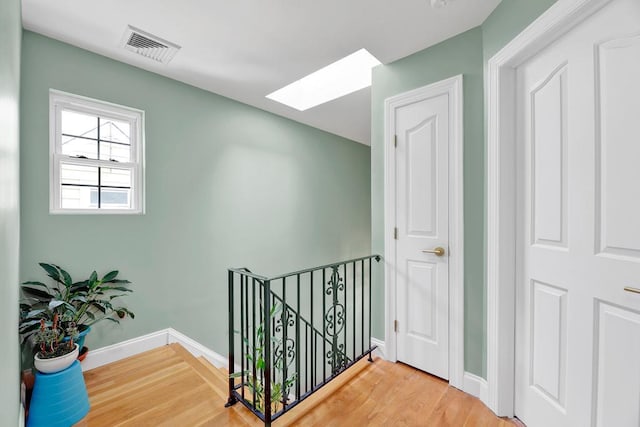 hallway featuring wood-type flooring and a skylight