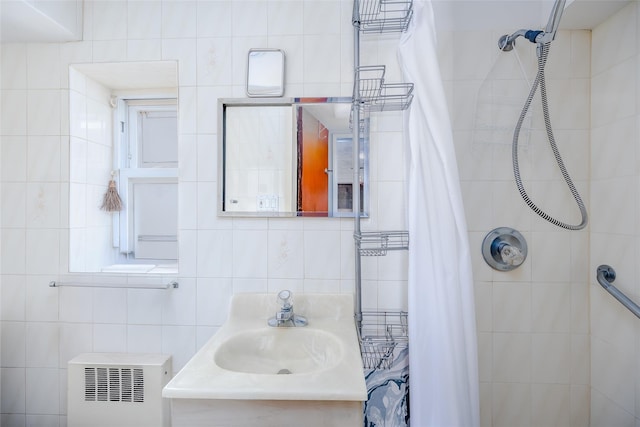 bathroom with walk in shower, radiator, sink, and tile walls