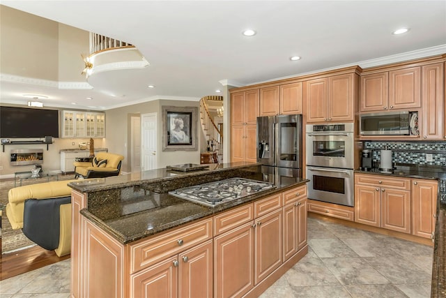 kitchen with crown molding, dark stone countertops, stainless steel appliances, a center island, and tasteful backsplash