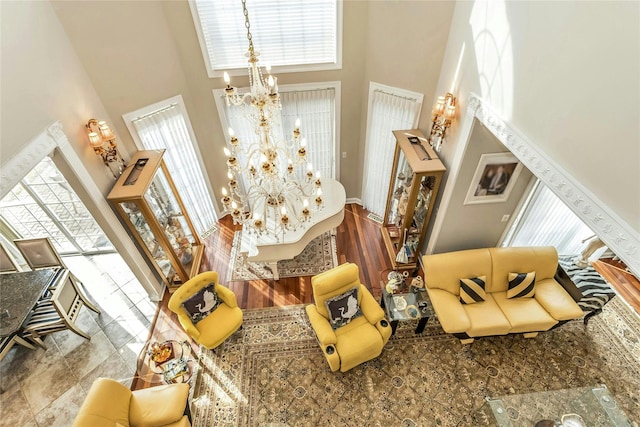 sitting room with a towering ceiling, light wood-style floors, and a notable chandelier