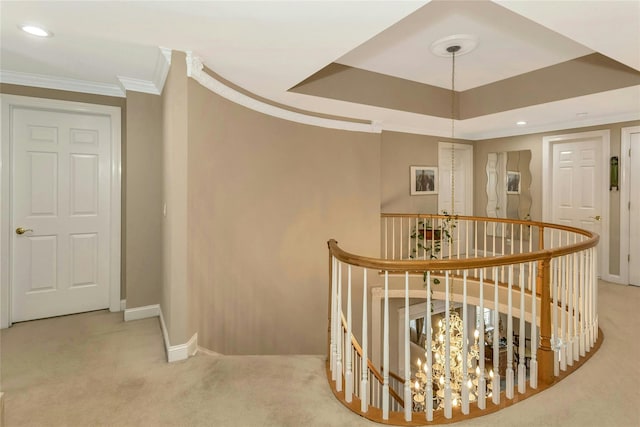 corridor featuring light colored carpet, an upstairs landing, baseboards, ornamental molding, and a raised ceiling