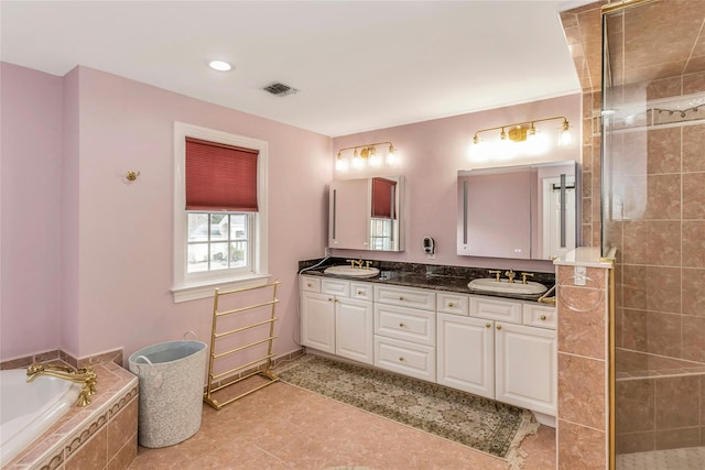 bathroom featuring double vanity, a garden tub, visible vents, and a sink