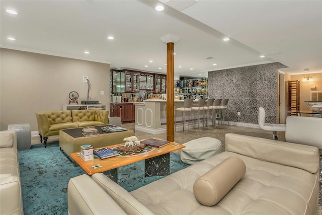 living room featuring indoor bar, ornamental molding, and decorative columns