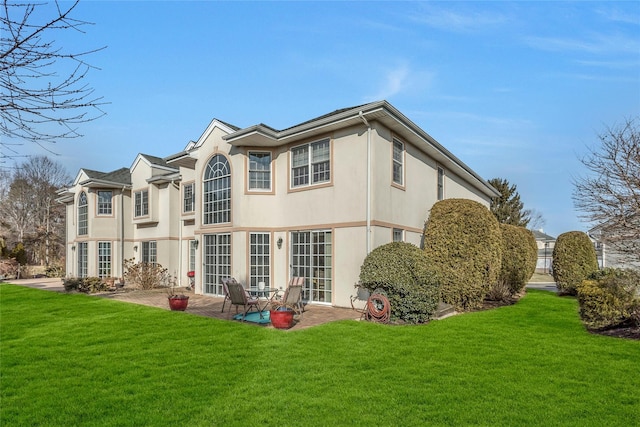 rear view of property featuring a yard, a patio area, and stucco siding