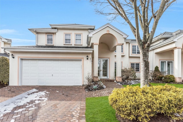 view of front of property featuring a garage, decorative driveway, and stucco siding