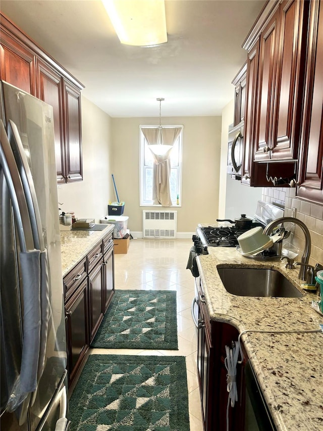 kitchen with sink, backsplash, hanging light fixtures, radiator heating unit, and stainless steel appliances