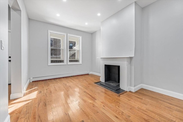 unfurnished living room featuring baseboard heating and light wood-type flooring