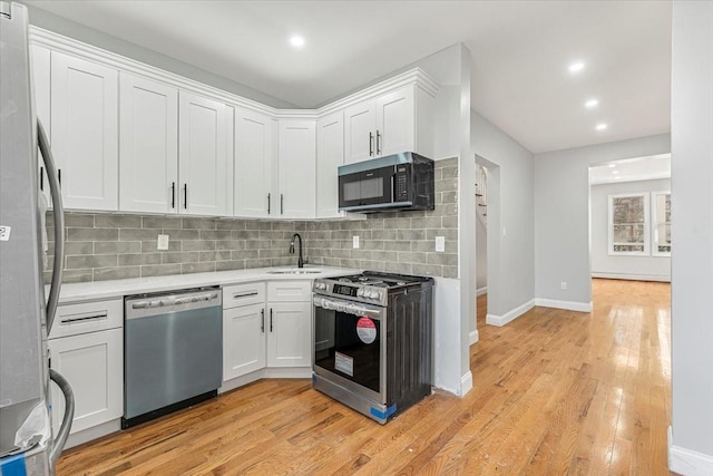 kitchen featuring stainless steel appliances, sink, white cabinets, and light hardwood / wood-style floors