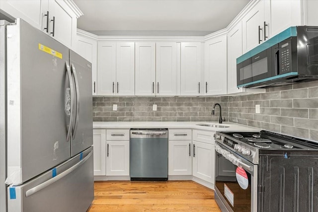 kitchen with stainless steel appliances, white cabinetry, and sink