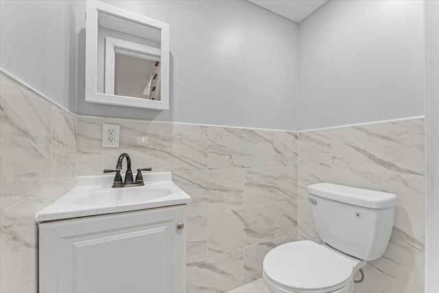 bathroom with vanity, toilet, and tile walls