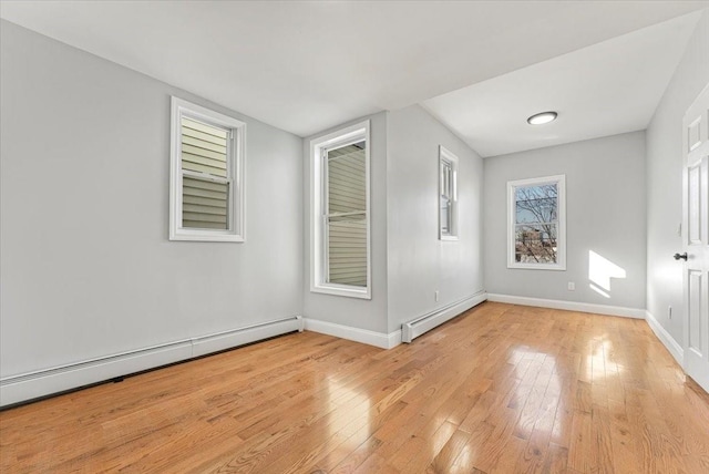 empty room featuring a baseboard heating unit and light hardwood / wood-style flooring