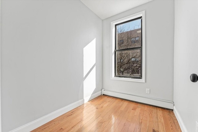 spare room featuring a baseboard radiator and light hardwood / wood-style floors