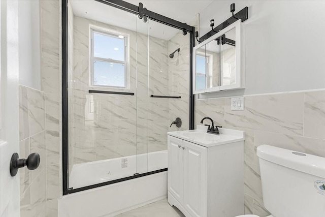 full bathroom with vanity, tile walls, shower / bath combination with glass door, and toilet