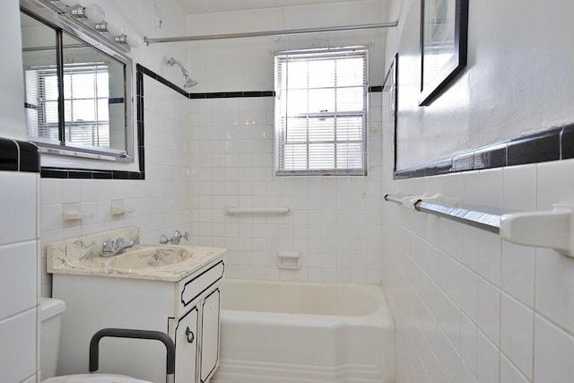 full bathroom featuring tile walls, vanity, tiled shower / bath, and toilet