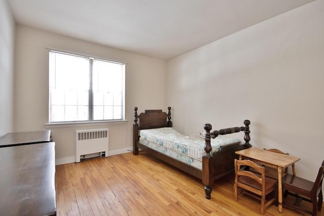 bedroom featuring radiator and light hardwood / wood-style floors