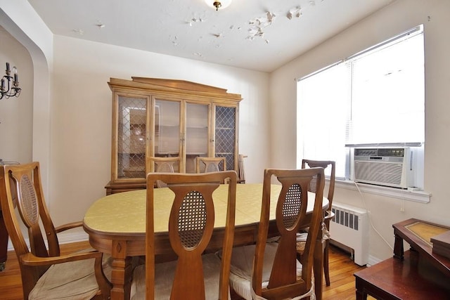 dining space with hardwood / wood-style floors, radiator heating unit, and cooling unit