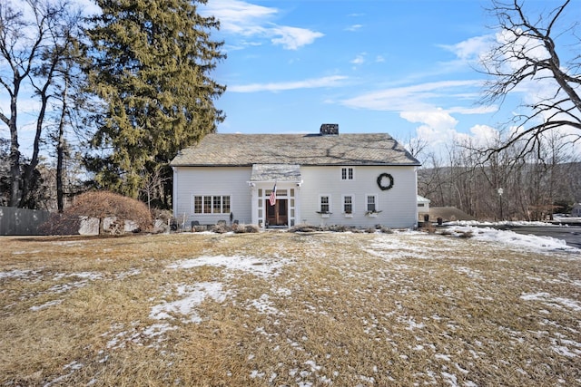 snow covered back of property featuring a chimney