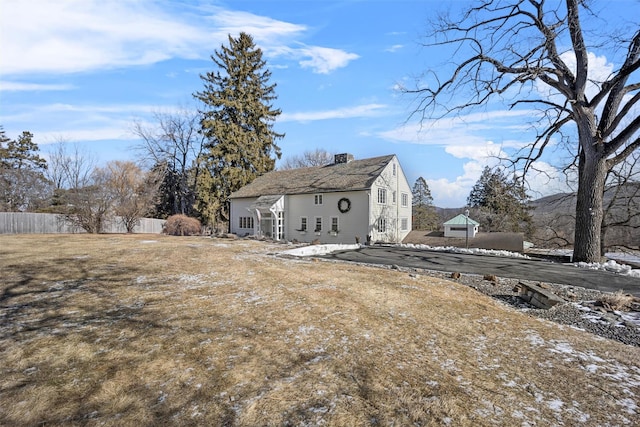 rear view of property featuring fence and a chimney