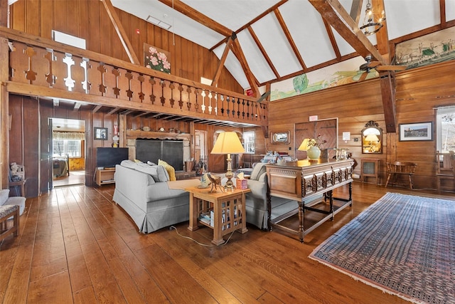 living room featuring ceiling fan, wood finished floors, beamed ceiling, wood walls, and high vaulted ceiling