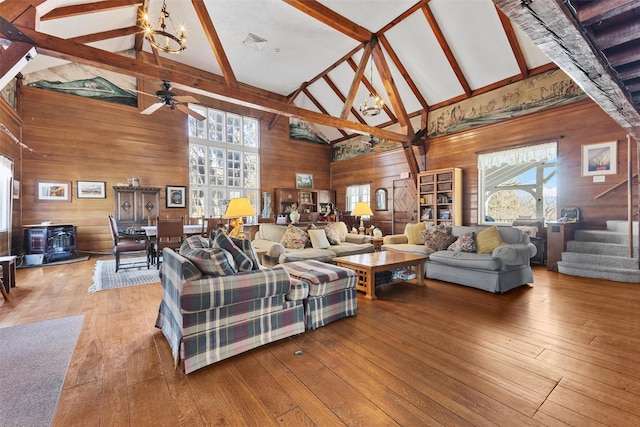 living room with wooden walls, a wood stove, stairway, and wood finished floors