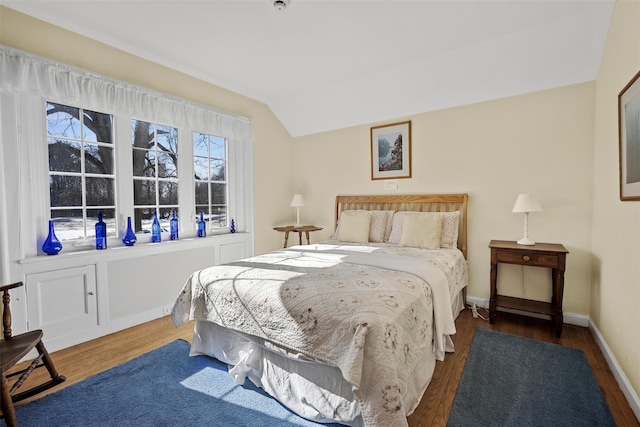 bedroom with baseboards, vaulted ceiling, and wood finished floors