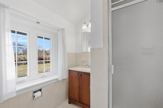 bathroom with a wealth of natural light, tile walls, a shower stall, and vanity