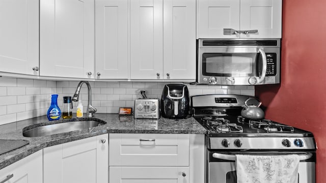 kitchen with backsplash, stainless steel appliances, sink, and white cabinets