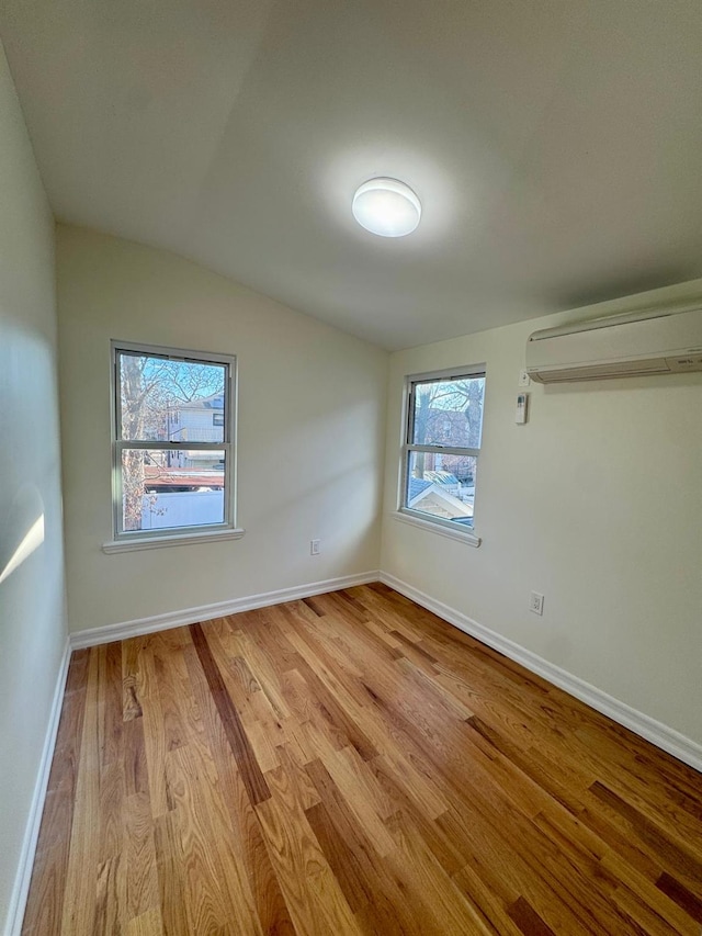 interior space featuring lofted ceiling, a wall unit AC, and light wood-type flooring