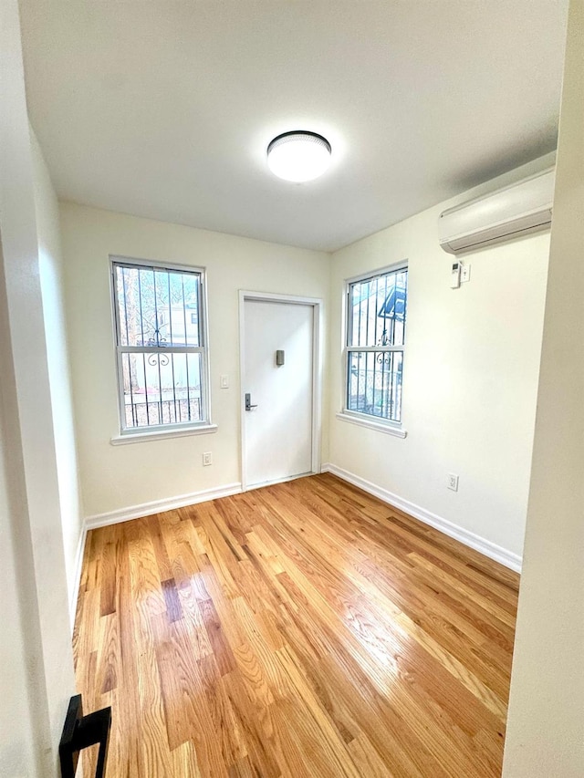 interior space featuring a healthy amount of sunlight, light wood-type flooring, and an AC wall unit