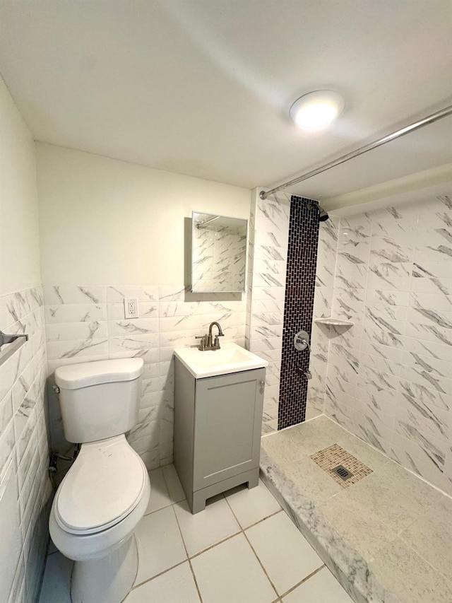 bathroom featuring tiled shower, vanity, toilet, and tile walls