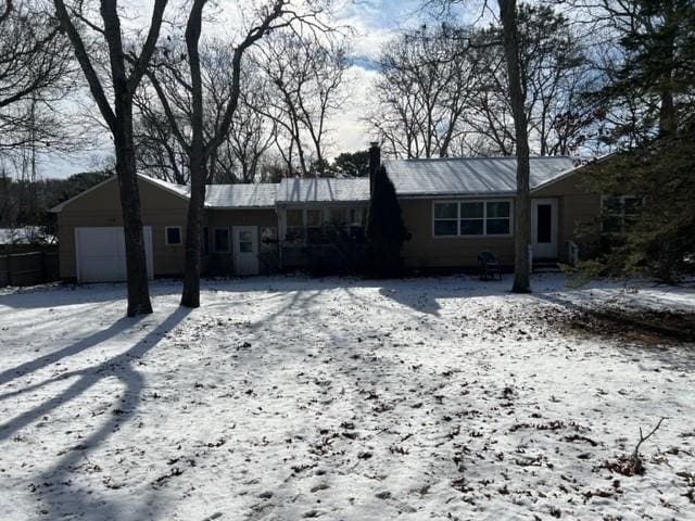 snow covered rear of property with a garage