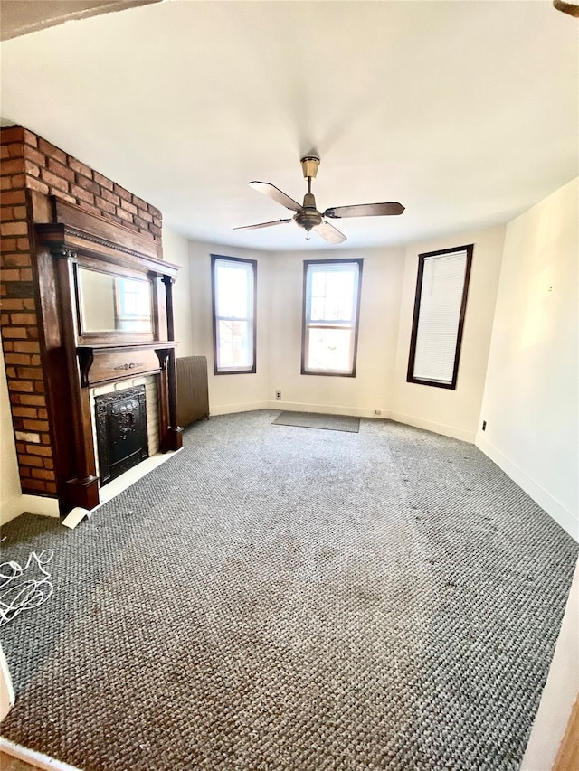 unfurnished living room featuring a large fireplace, ceiling fan, and carpet