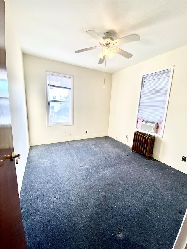 spare room featuring cooling unit, ceiling fan, radiator, and dark carpet