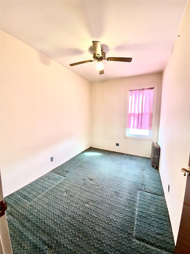 carpeted empty room featuring radiator and ceiling fan