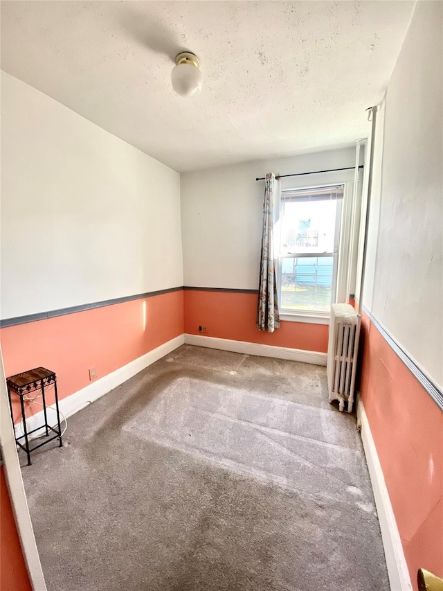 unfurnished room with radiator, a textured ceiling, and carpet flooring