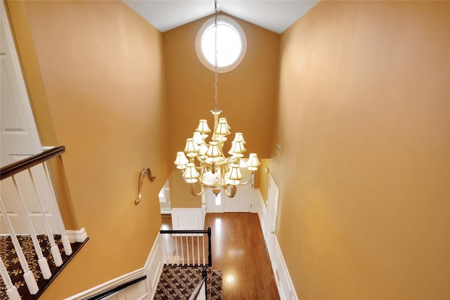 stairs with hardwood / wood-style flooring, a chandelier, and high vaulted ceiling