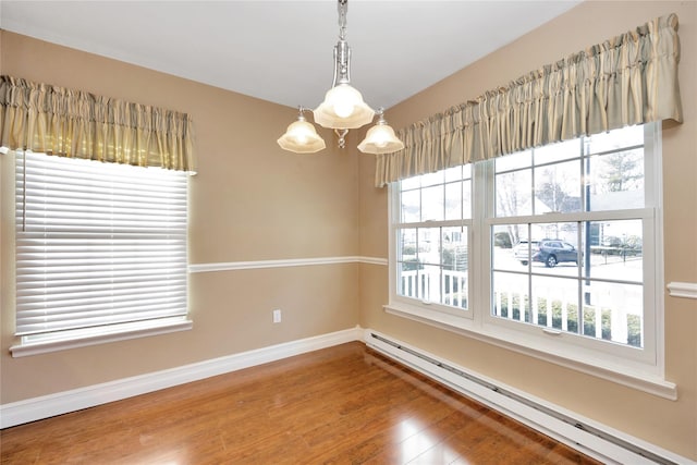 empty room featuring hardwood / wood-style floors, a notable chandelier, and baseboard heating