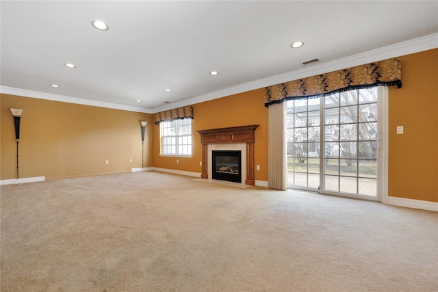 unfurnished living room with a tiled fireplace, crown molding, and light colored carpet