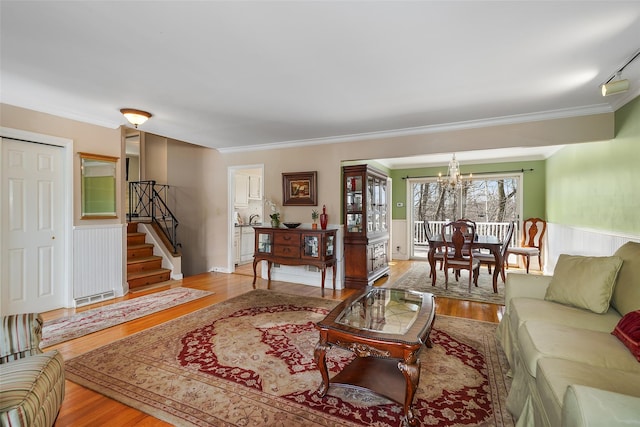 living room with stairs, crown molding, a notable chandelier, and wood finished floors