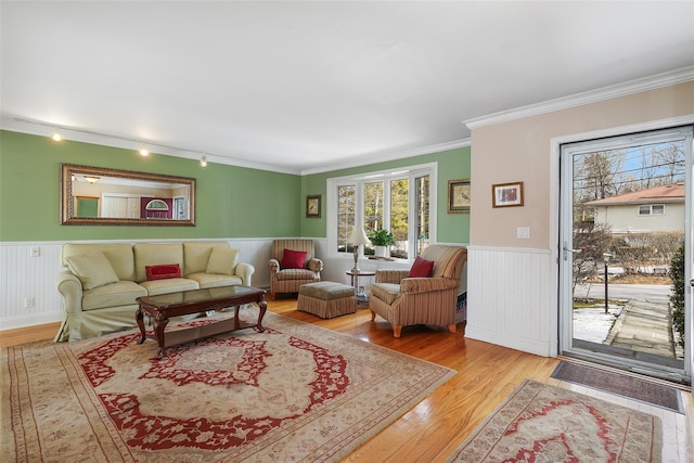 living room featuring track lighting, wainscoting, crown molding, and wood finished floors