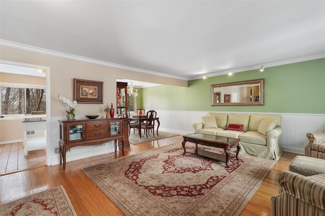 living area featuring ornamental molding, wainscoting, and light wood finished floors