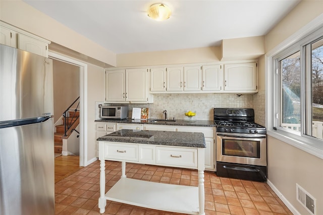 kitchen with a sink, visible vents, white cabinetry, appliances with stainless steel finishes, and tasteful backsplash